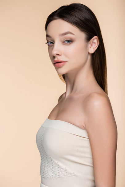 confident young woman in crop top with bare shoulders isolated on beige  - Фото, зображення