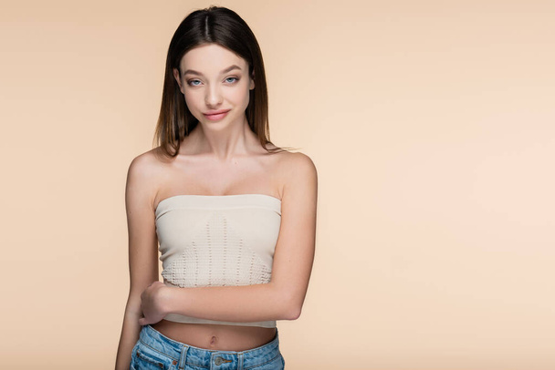 smiling and pretty woman in crop top isolated on beige  - Foto, Imagem