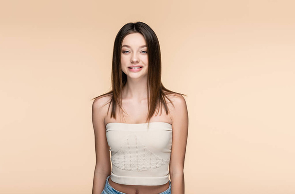 positive and pretty woman in crop top isolated on beige  - Foto, Bild