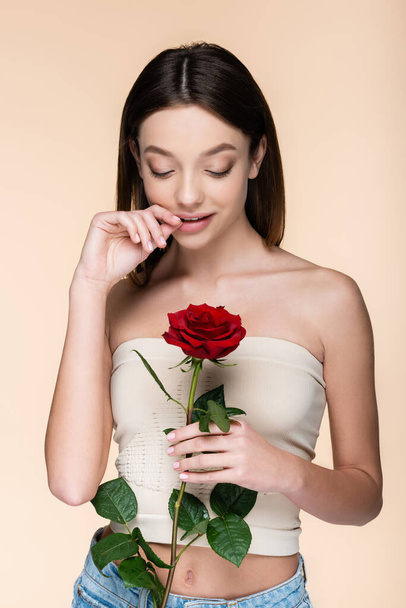 flirty woman with bare shoulders holding red rose isolated on beige  - Photo, Image