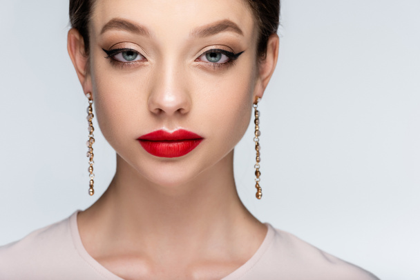 pretty woman in earrings with bright makeup looking at camera isolated on grey - Fotoğraf, Görsel