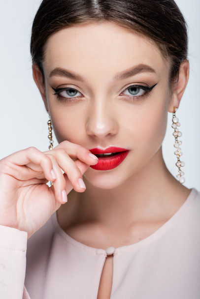 flirty young woman in earrings touching lips isolated on grey - Fotografie, Obrázek