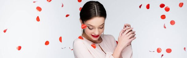 young and happy woman near falling rose petals on grey, banner - Photo, image