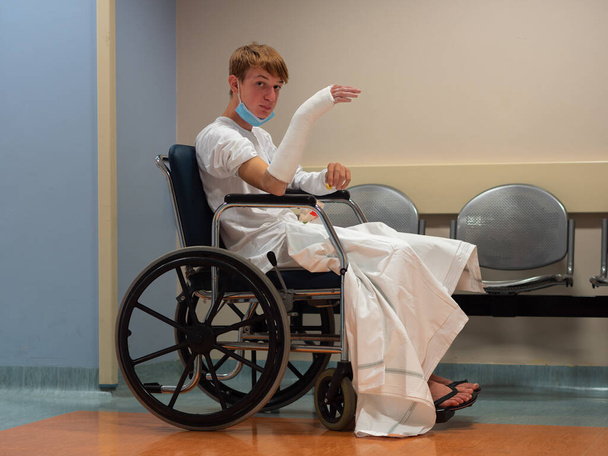Yaralandıktan kısa bir süre sonra Kol ve Bilekle Tekerlekli Sandalyede Oturan Genç Çocuk. - Fotoğraf, Görsel