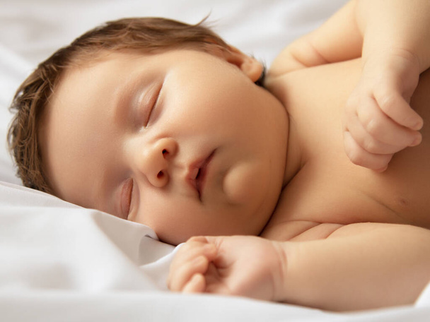 Small baby girl sleeping. Newborn baby in a wrap on white blanket. Beautiful portrait of little child girl 7 days, one week old. Baby lying on back on white background. Motherhood - Foto, immagini