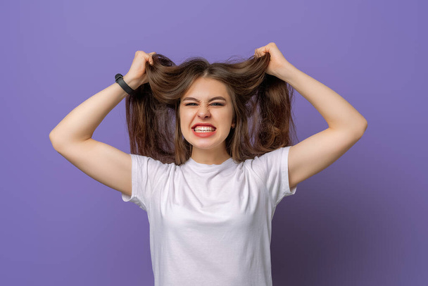 Brunette Girl start panic worried nothing prepared in time, standing shocked stunned grab head concerned grimacing bothered standing nervous, while standing over purple background - Photo, Image