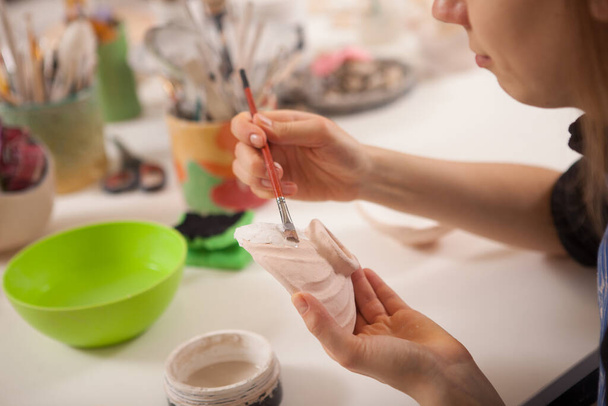 Cropped close up of a woman painting clay bowl at pottery school - 写真・画像