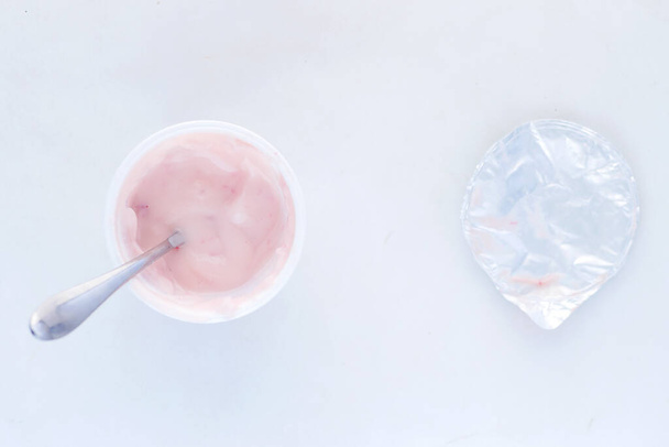 fresh yogurt in a plastic container and spoon on table  - Fotografie, Obrázek