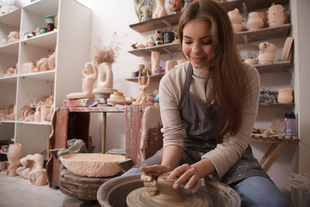 Low angle shot of a young beautiful woman enjoying working with clay, using potters wheel, copy space - Fotografie, Obrázek