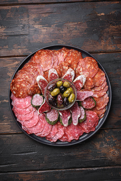 Antipasti-Platte mit kaltem Fleisch mit Chorizo, Fuet, Salami, Salchichon und Longaniza auf dunklem Holzgrund. - Foto, Bild