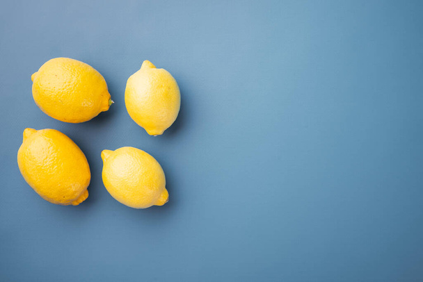 Whole ripe lemon set, on blue textured summer background, with copy space for text - Photo, image