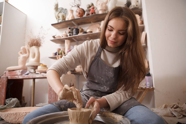 Low angle shot of beautiful woman enjoying working with clay on a potters wheel at crafts studio - Foto, imagen
