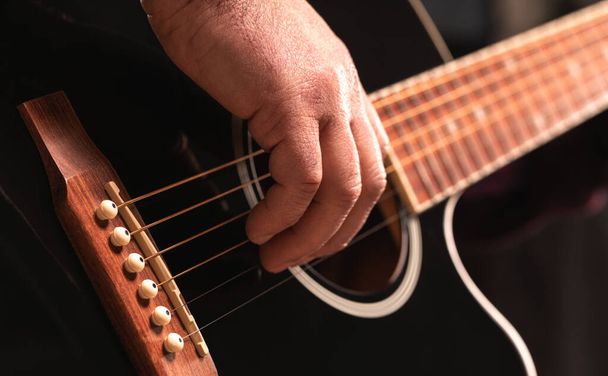 man playing guitar, hands on strings close-up - Foto, afbeelding
