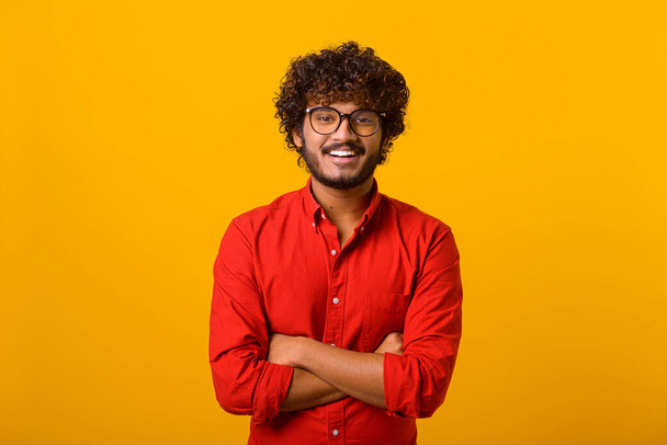 Portrait of bearded handsome man with black glasses in casual style looking at camera and smiling. Studio shot on orange - Photo, image