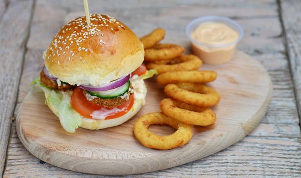Fresh and fried fish burger with vegetables and onion rings - Fotografie, Obrázek