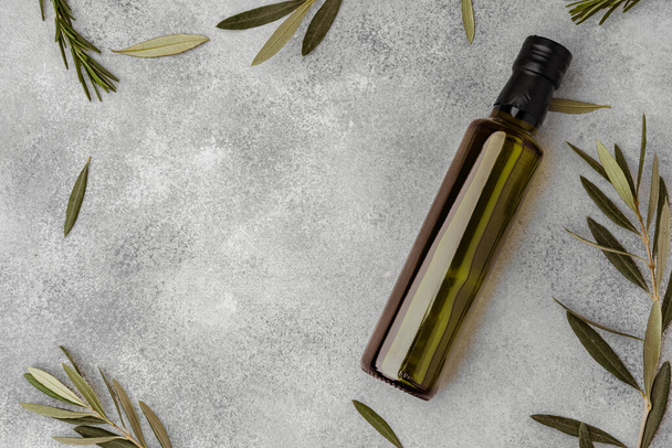 Harmaalla pohjalla oliiviöljyä sisältävä lasipullo - Valokuva, kuva