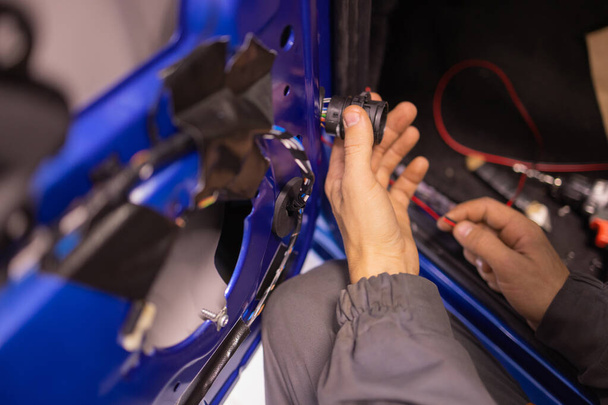 Auto repair technicians in car repair shops are repairing car door systems and repairing electric vehicle systems. - Foto, Bild