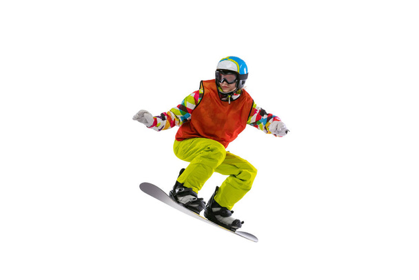 One young woman in bright sportswear, goggles and helmet snowboarding isolated on white studio background. Concept of winter sports - Фото, зображення