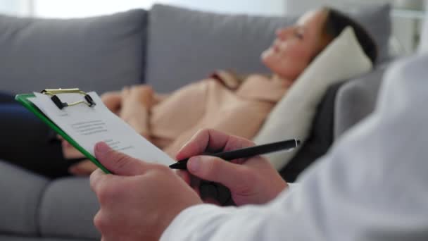 Κοντινό πλάνο άνθρωπος ψυχοθεραπευτής κρατώντας σημειώσεις στο πρόχειρο και να ακούσετε γυναίκα ασθενή - Πλάνα, βίντεο