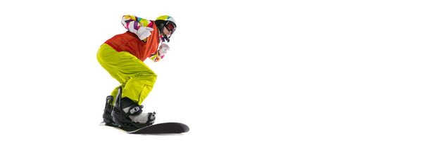 One young woman in bright sportswear, goggles and helmet snowboarding isolated on white studio background. Concept of winter sports - Фото, зображення