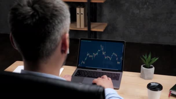 Man professional stock trader broker uses laptop with stock exchange chart - Filmati, video