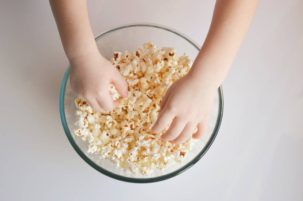 children's hands take popcorn in a plate. background for popcorn and movie day decoration. - Fotoğraf, Görsel