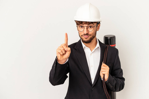 Jeune architecte mixte homme portant un casque isolé sur fond gris montrant numéro un avec doigt. - Photo, image