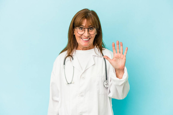 Middle age doctor woman isolated on pink background smiling cheerful showing number five with fingers. - Foto, immagini