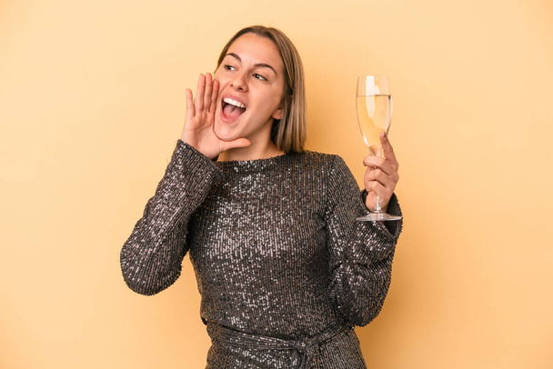 Young caucasian woman celebrating new year isolated on yellow background shouting and holding palm near opened mouth. - Φωτογραφία, εικόνα