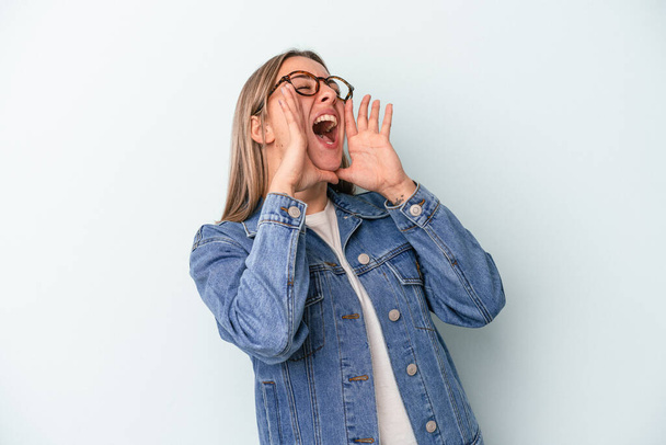 Young caucasian woman isolated on blue background shouting excited to front. - Photo, Image