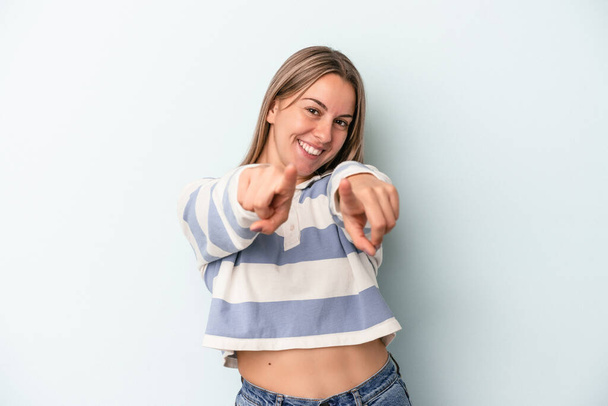 Young caucasian woman isolated on blue background pointing to front with fingers. - Photo, Image