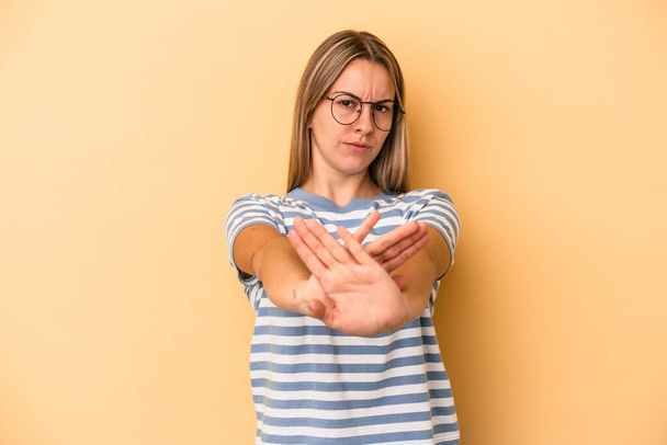 Junge kaukasische Frau isoliert auf gelbem Hintergrund stehend mit ausgestreckter Hand Stoppschild zeigt, verhindert, dass Sie. - Foto, Bild