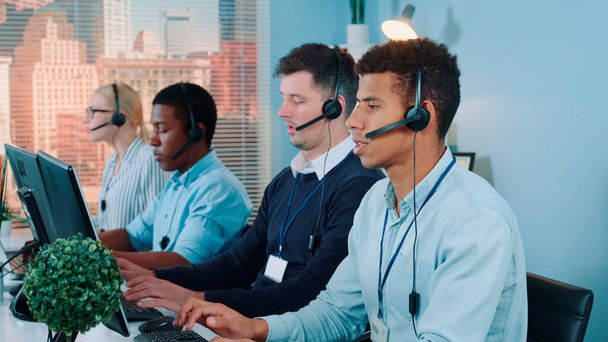 Medium shot van Multiraciale call center agenten praten met de klanten in headset - Foto, afbeelding