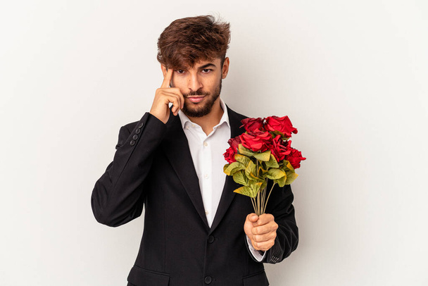 Young mixed race man holding bouquet of roses isolated on white background pointing temple with finger, thinking, focused on a task. - Zdjęcie, obraz