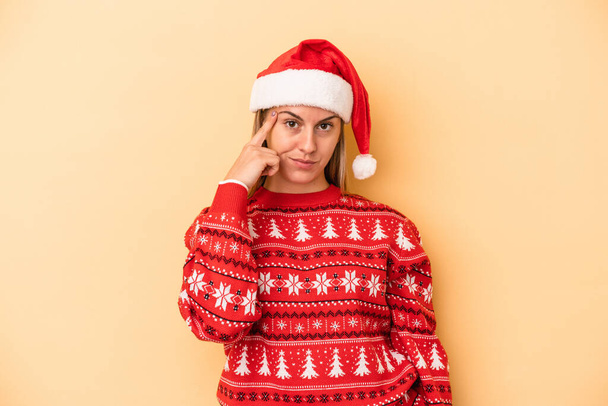 Young caucasian woman celebrating Christmas isolated on yellow background pointing temple with finger, thinking, focused on a task. - Fotografie, Obrázek