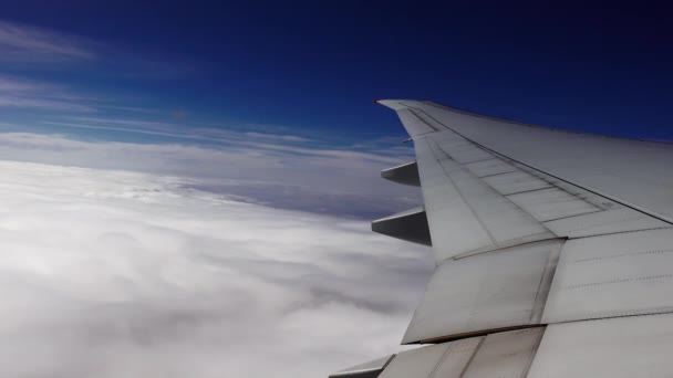 Το ατσάλινο φτερό ενός αεροπλάνου που πετάει πάνω από τα σύννεφα στον γαλάζιο ουρανό - Πλάνα, βίντεο