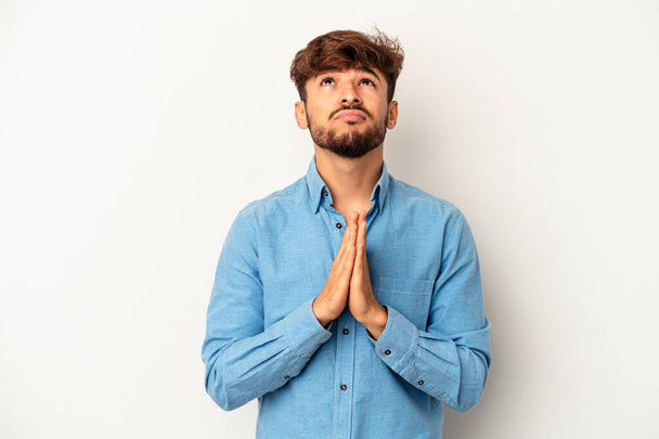 Young mixed race man isolated on grey background holding hands in pray near mouth, feels confident. - Foto, Bild