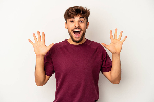 Young mixed race man isolated on grey background receiving a pleasant surprise, excited and raising hands. - Fotografie, Obrázek