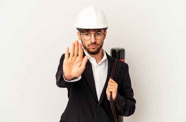 Young mixed race architect man wearing a helmet isolated on grey background standing with outstretched hand showing stop sign, preventing you. - Photo, Image