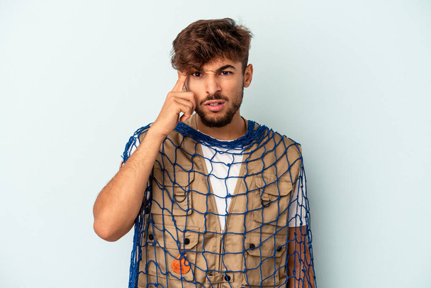 Young mixed race fisherman holding a net isolated on blue background showing a disappointment gesture with forefinger. - Fotó, kép