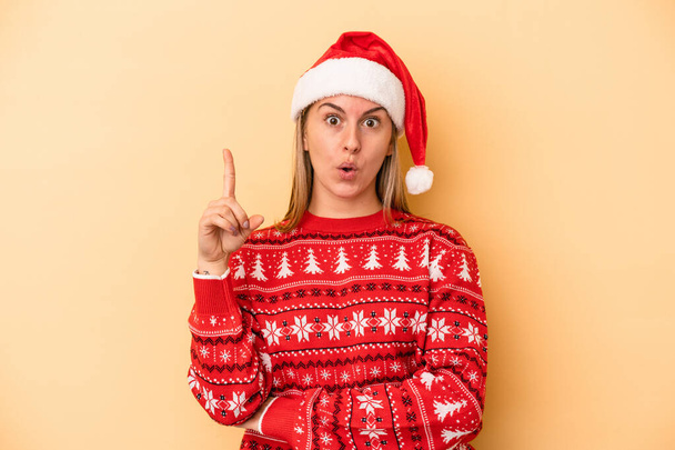 Young caucasian woman celebrating Christmas isolated on yellow background having some great idea, concept of creativity. - Фото, изображение