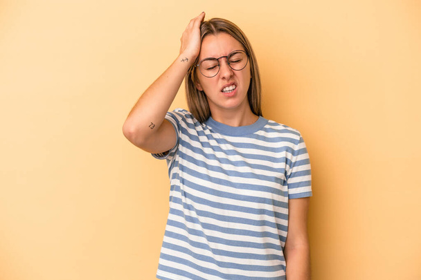 Young caucasian woman isolated on yellow background forgetting something, slapping forehead with palm and closing eyes. - Photo, Image