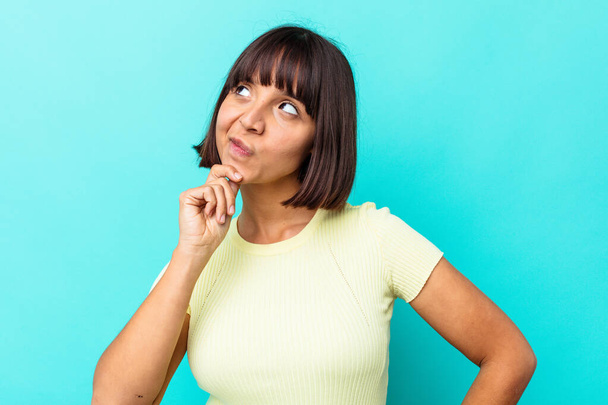 Young mixed race woman isolated on blue background relaxed thinking about something looking at a copy space. - Photo, Image