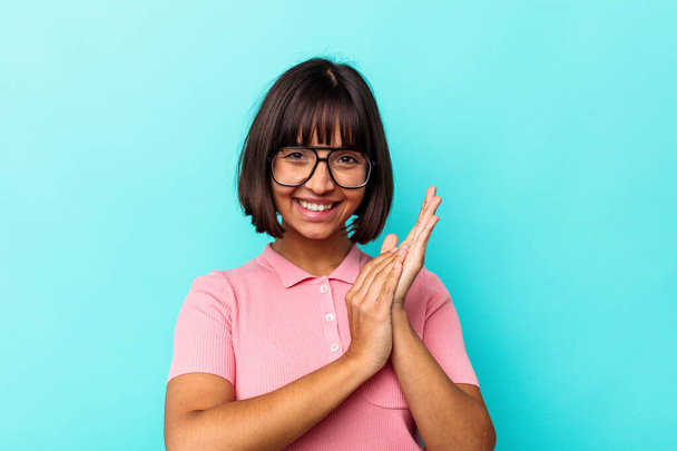 Young mixed race woman isolated on blue background feeling energetic and comfortable, rubbing hands confident. - Photo, Image