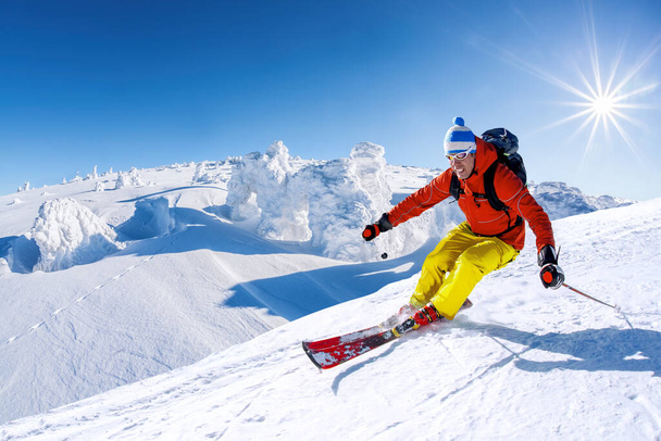Skifahrer fährt im Hochgebirge vor blauem Himmel abwärts - Foto, Bild