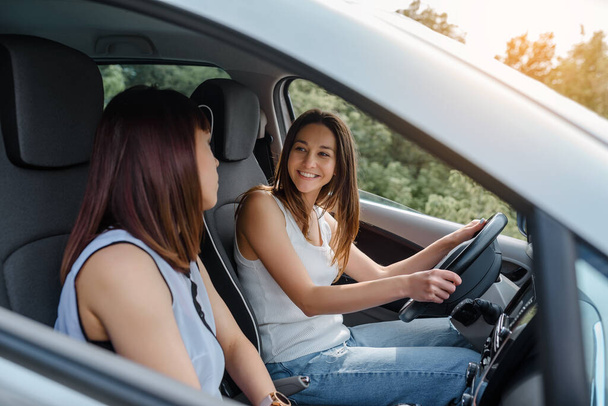 Kaksi onnellista nuorta naista ystävät ajavat autoa ja nauttia yrityksestä. Matkustaa ystäväsi käsite - Valokuva, kuva