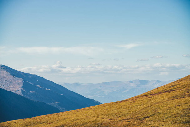 Paysage automnal minimaliste avec diagonale de montagne orange ensoleillée sur fond de silhouettes de montagnes à l'horizon. Paysage de montagne minime avec pente de colline au soleil doré en automne - Photo, image