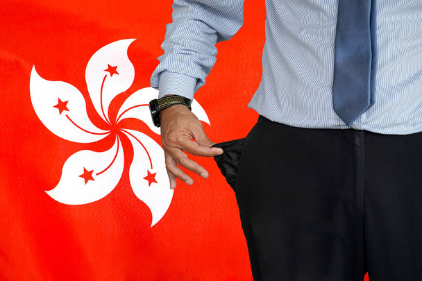 Hand of man in suit turning pocket of his trousers inside out and showing it empty on the background of the Hong Kong flag. Crisis, unemployment, bankruptcy concept in Hong Kong - Фото, изображение