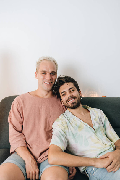 Gay couple sitting on sofa in their house - Fotó, kép