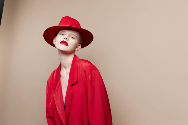 elbűvölő nő piros kabát és kalap piros ajkak divat bézs háttér - Fotó, kép